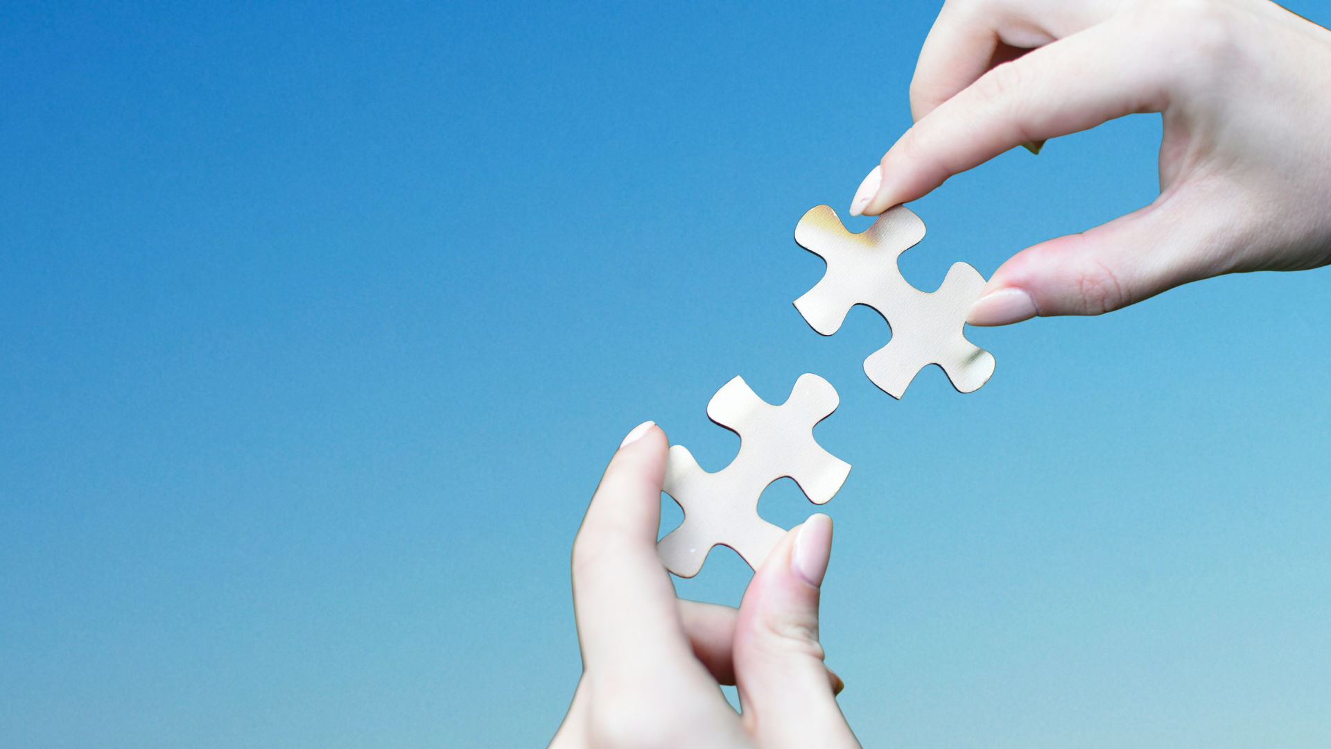 Hands holding two jigsaw pieces that clearly connect.